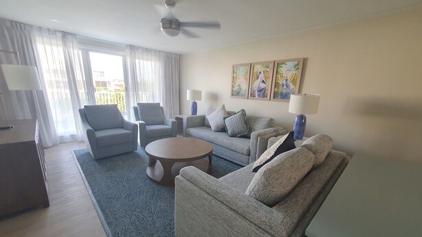 Ein modernes Wohnzimmer mit einer Couch, Sesseln, einem Couchtisch und Kunstwerken an der Wand.
