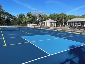 Pistas de tenis múltiples, rodeadas de árboles y zonas con sombra.