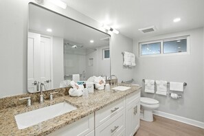 Un baño con dos lavamanos, un inodoro, un espejo grande y una ventana.