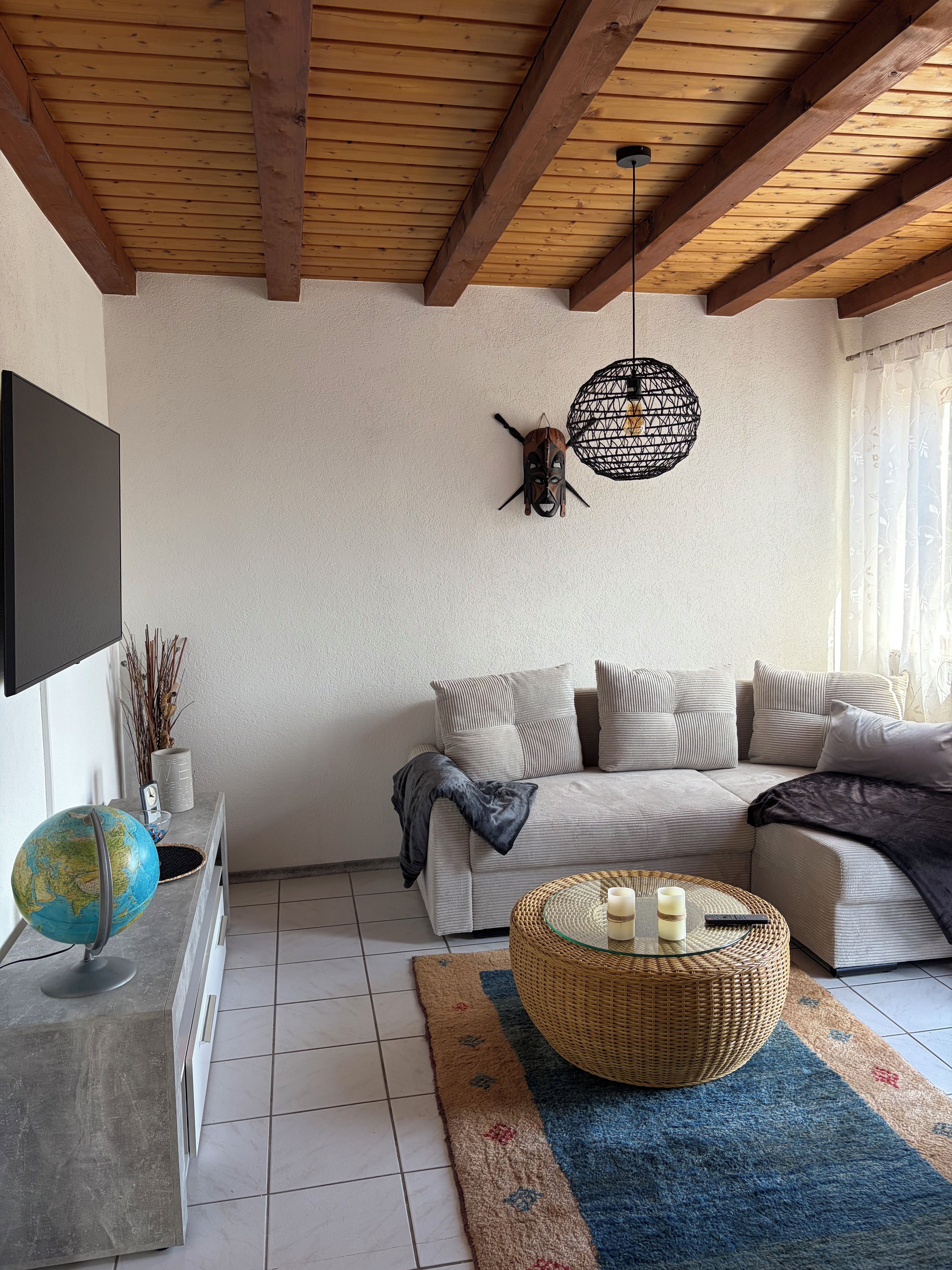A living room with a sofa, a globe, a wall-mounted light fixture, and a woven basket on the floor.