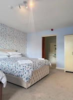 A bedroom with a bed, a wardrobe, and a bathroom visible through an open door.