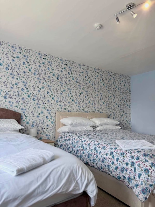 A bedroom with two beds, a headboard, and a ceiling light fixture.