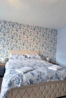A bedroom with a bed, floral wallpaper, and two bedside lamps.