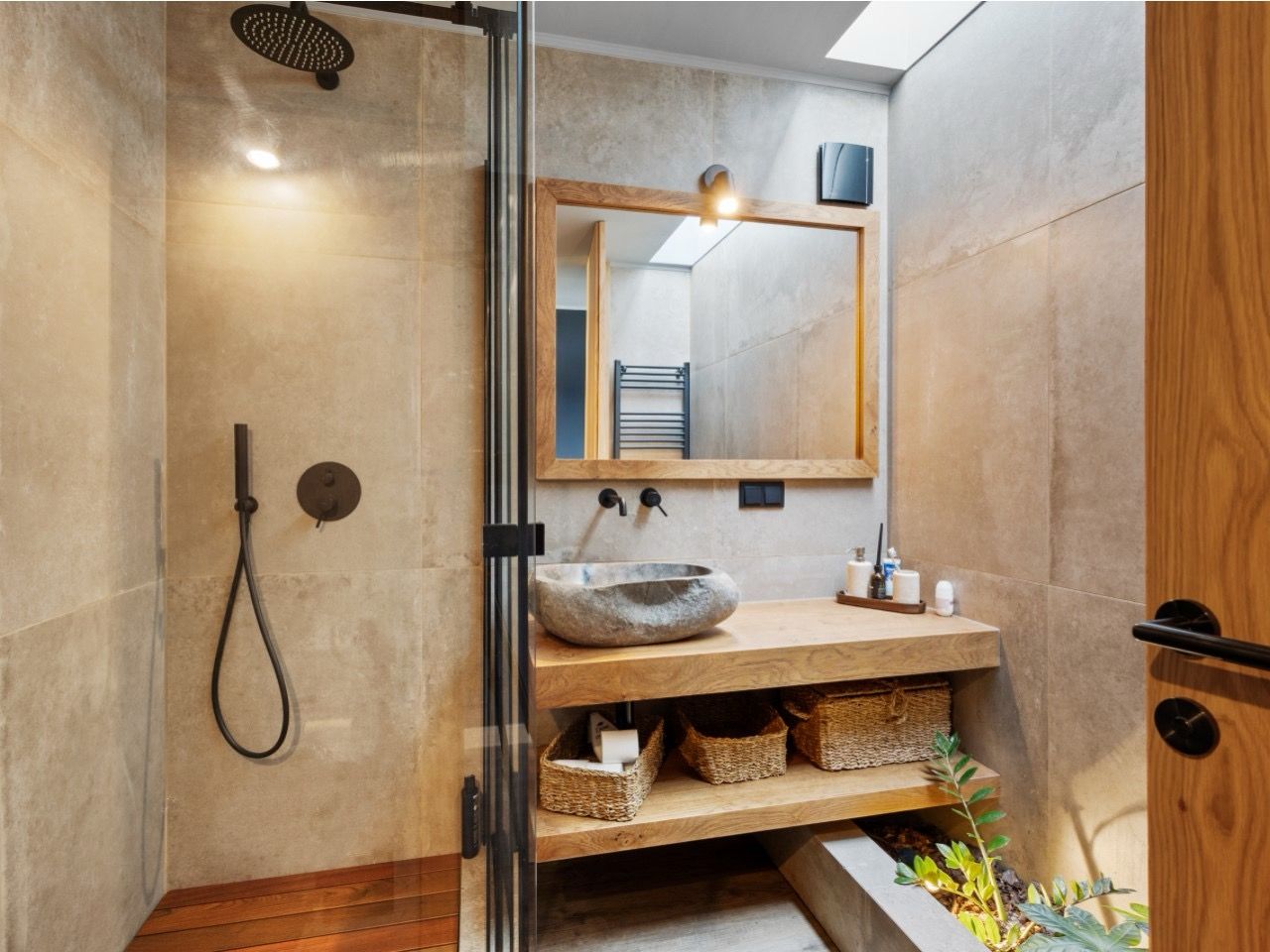 A modern bathroom with a glass shower enclosure, a wooden vanity, and a large mirror.
