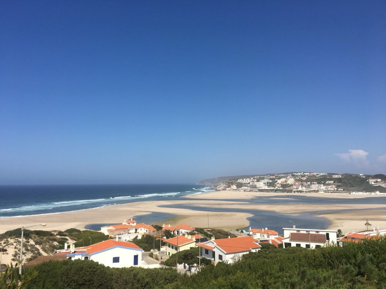 A coastal town with buildings near the beach, clear skies, and a view of the ocean.