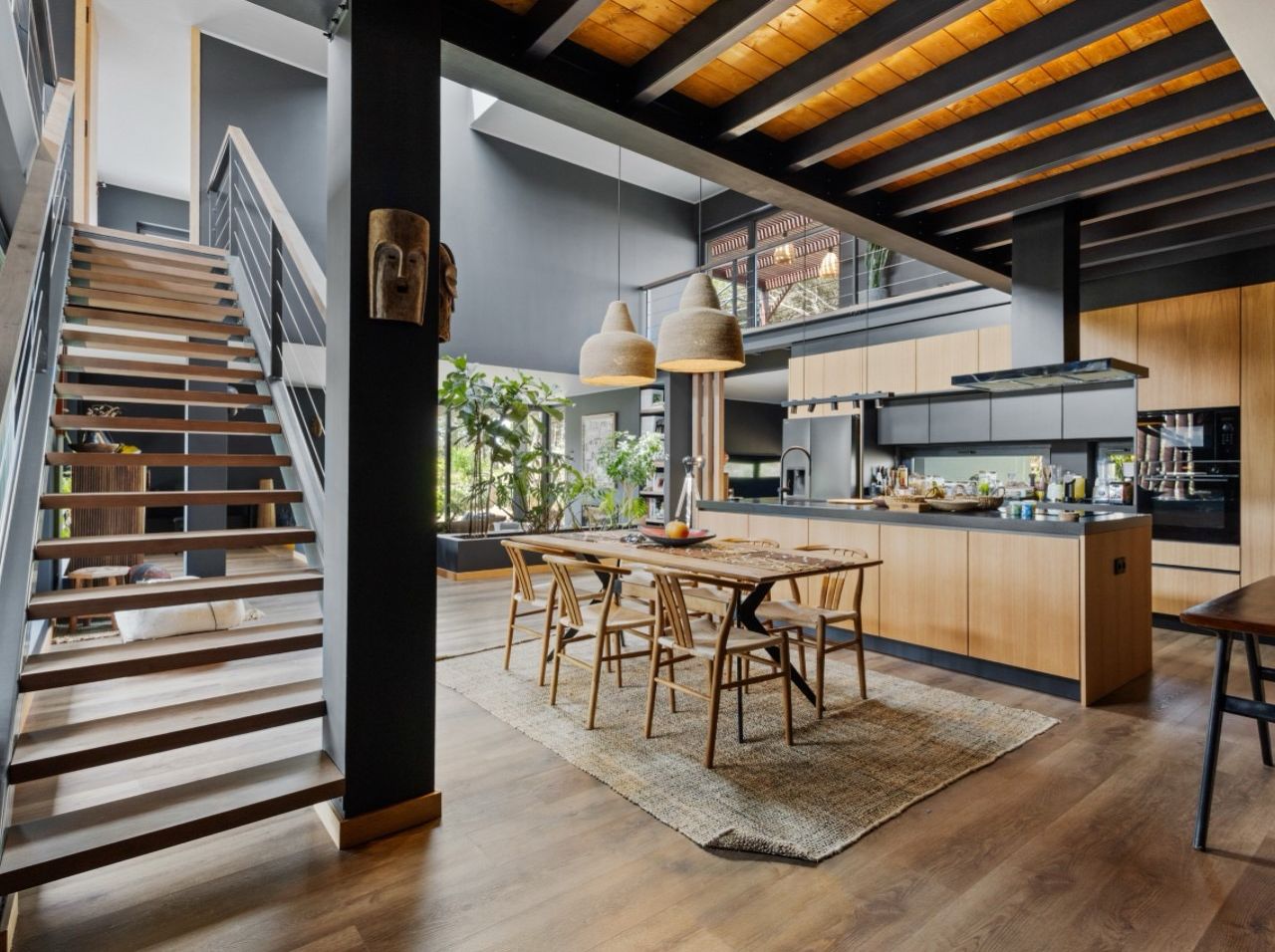 A modern kitchen with a central island, wooden flooring, and pendant lighting.