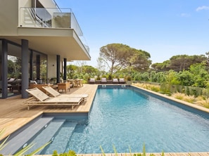 Ein moderner Poolbereich mit Liegestühlen und einer Holzterrasse.