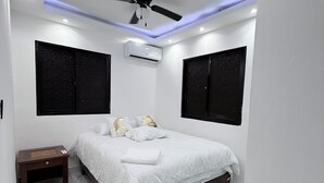 Ein Schlafzimmer mit einem Bett, einem Nachttisch, einem Deckenventilator und einer Klimaanlage.