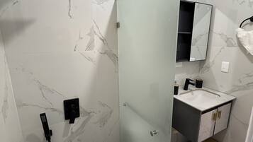 Une salle de bain avec une douche à parois de verre, un lavabo avec un miroir et des toilettes.