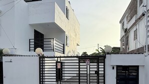 Ein befestigter Eingang zu einem Gebäude im modernen Architekturstil, mit einer glatten Fassade und einem großen, schwarzen Metallgitter.