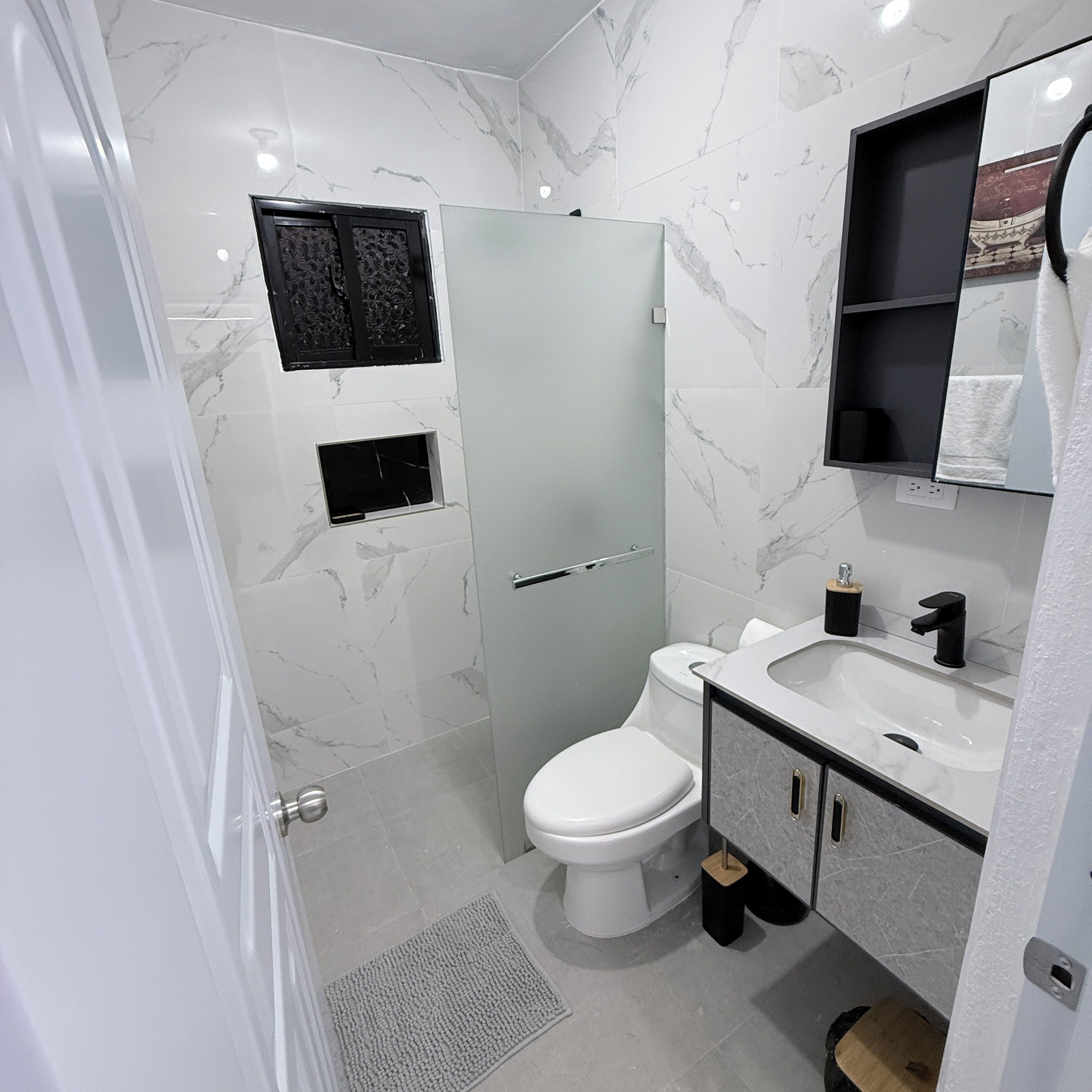 Een badkamer met toilet, wastafel en spiegel.