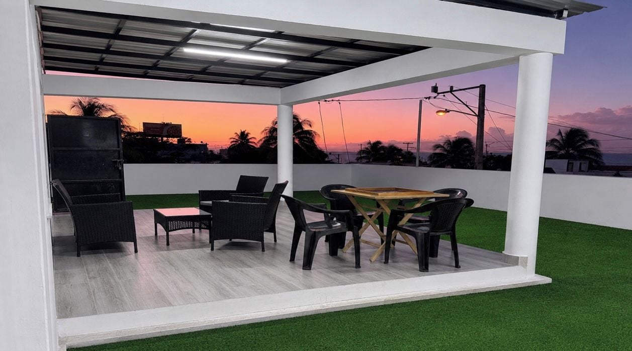 Ein überdachter Außenbereich mit Pooltisch, Stühlen und Blick auf den Sonnenuntergang.