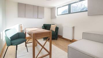 Een moderne woonkamer met een houten salontafel, een groene fauteuil, een grijze bank en een radiator.
