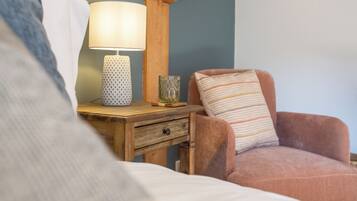 Een slaapkamer met een houten nachtkastje, een lamp, een glas en een gestreept kussen.