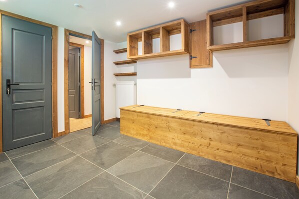 A hallway with a grey door, a wooden bench, and built-in shelves.