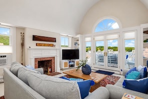 A spacious living room with a fireplace, a television, and a view of the outdoors through large windows. - Sea Spray
Charming Three Bedroom House with amazing views of Camden Harbor (Camden)