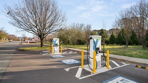 An electric vehicle charging station with a clear path marked for EVs, surrounded by trees and a parking lot. - Turner & Tonic at Avron City Escape (Turner)