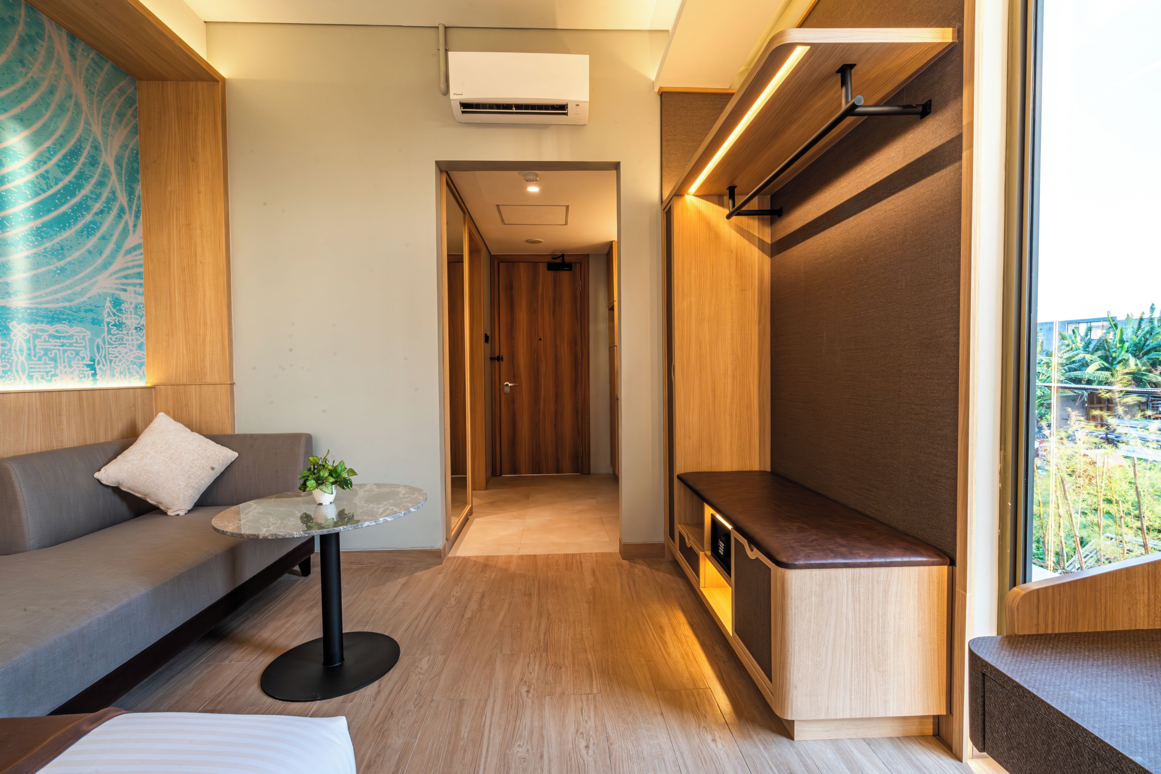 Ein modernes Interieur mit einer Couch, einem kleinen Tisch mit Pflanze, einer Bank und Blick durch ein Fenster.