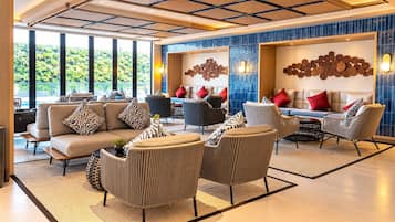 Um hall de hotel moderno com um conjunto de sofás, poltronas e uma mesa de centro.