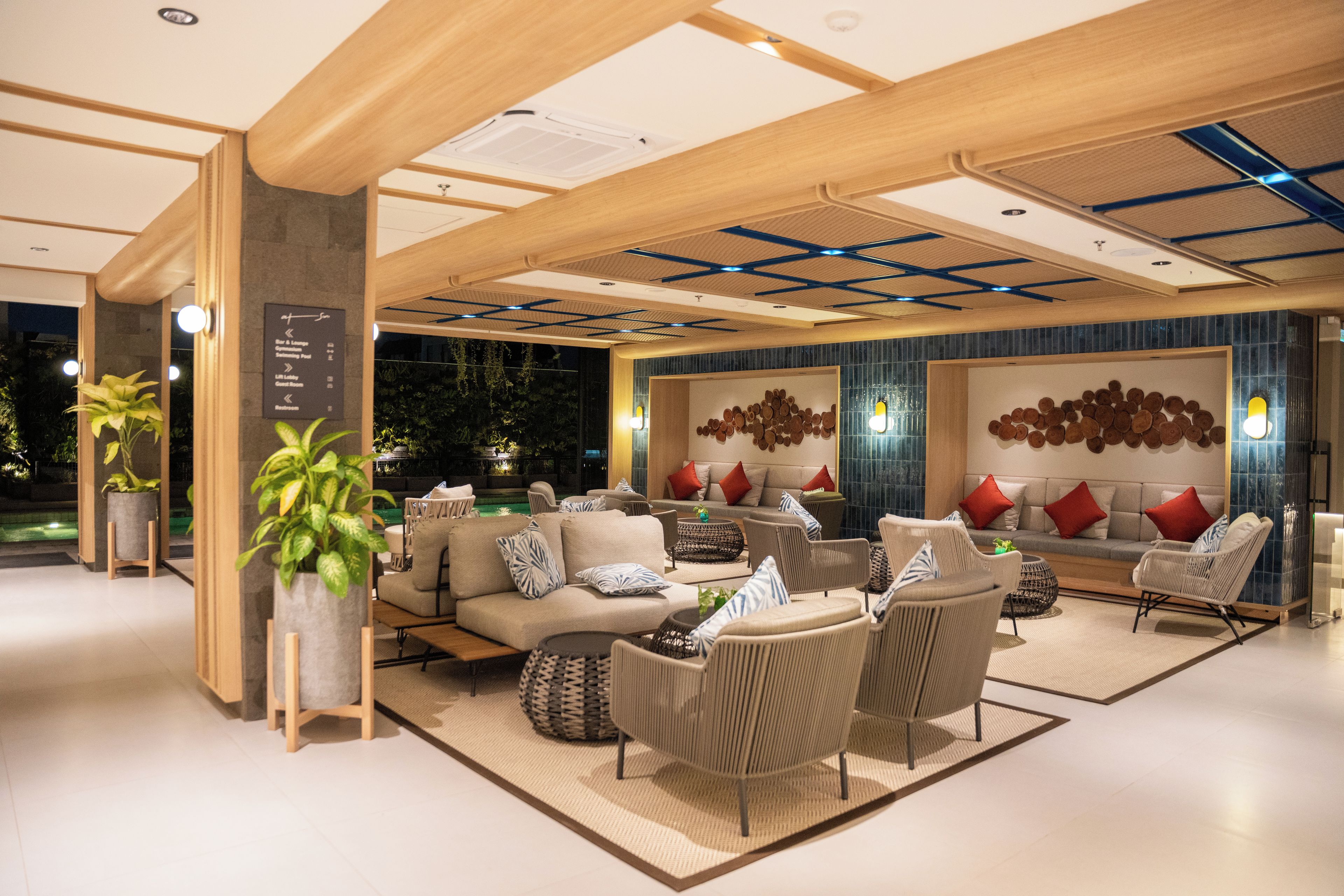 A modern lounge area with seating arrangements, a pool view, and a wall with a circular pattern.
