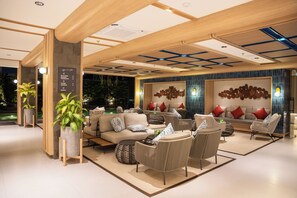 A modern lounge area with seating arrangements, a pool view, and a wall with a circular pattern. - ATSINI Pererenan (Pererenan)