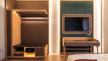A modern hotel room with a bed, a desk, a built-in wardrobe, and a mirror.