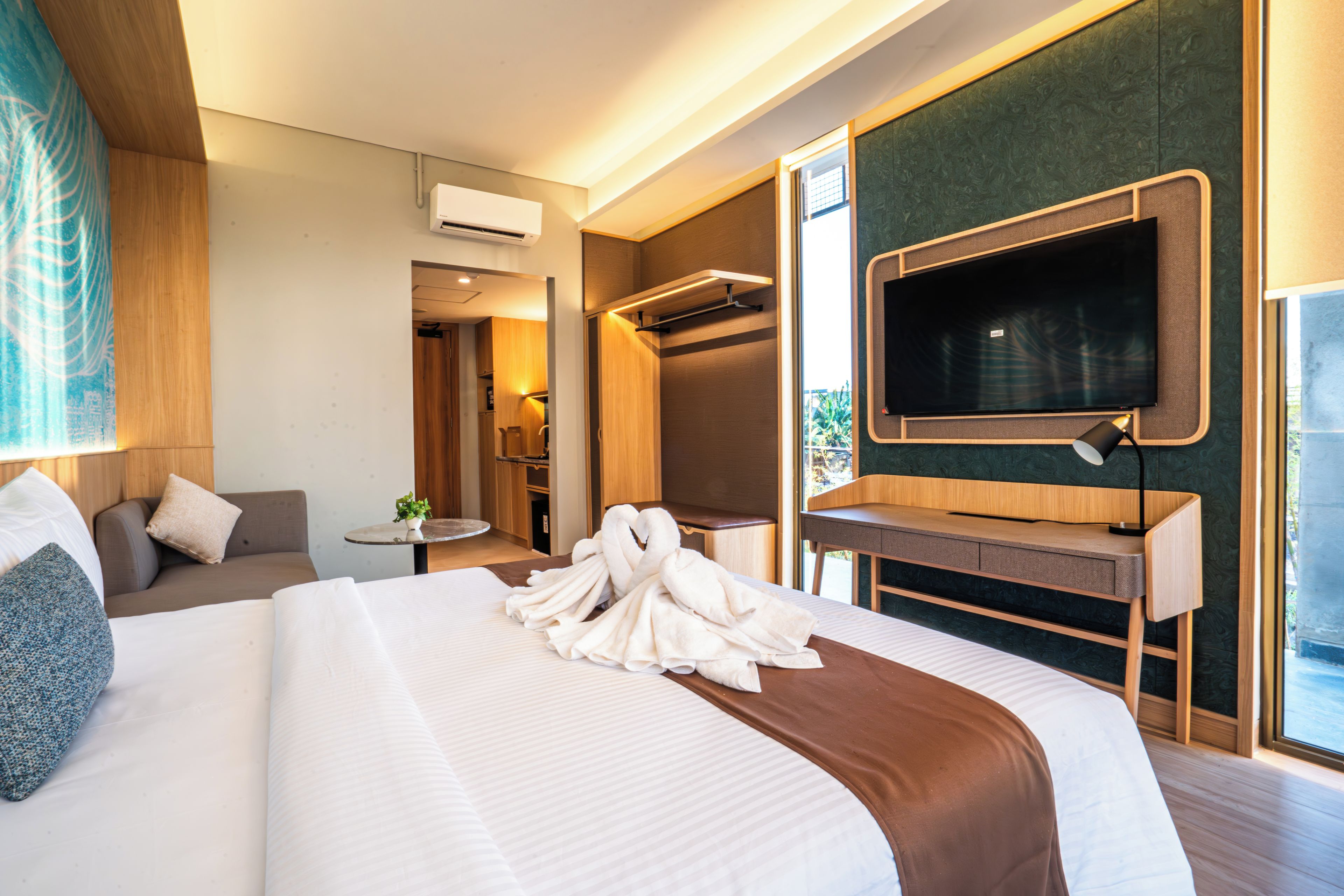Quarto de hotel com cama grande, escrivaninha, televisão e banheiro.