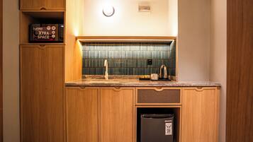 Een kleine keuken met houten kastjes, een ingebouwde magnetron en een roestvrijstalen koelkast.