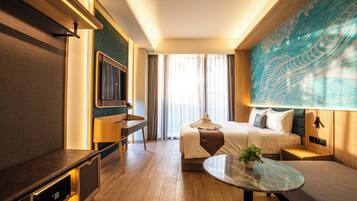 Een hotelkamer met een bed, een bureau, een televisie, een groot raam met gordijnen en een wand met een decoratief patroon.