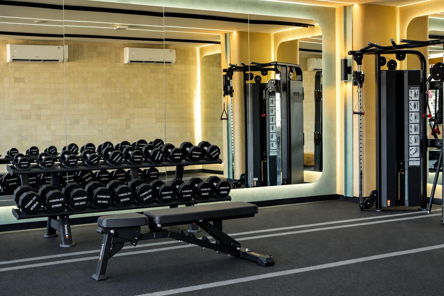 Une salle de sport équipée de matériel de musculation, notamment des haltères et un banc de développé couché.