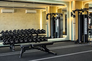 Un gimnasio con equipo de levantamiento de pesas, incluyendo mancuernas y una prensa de banca.