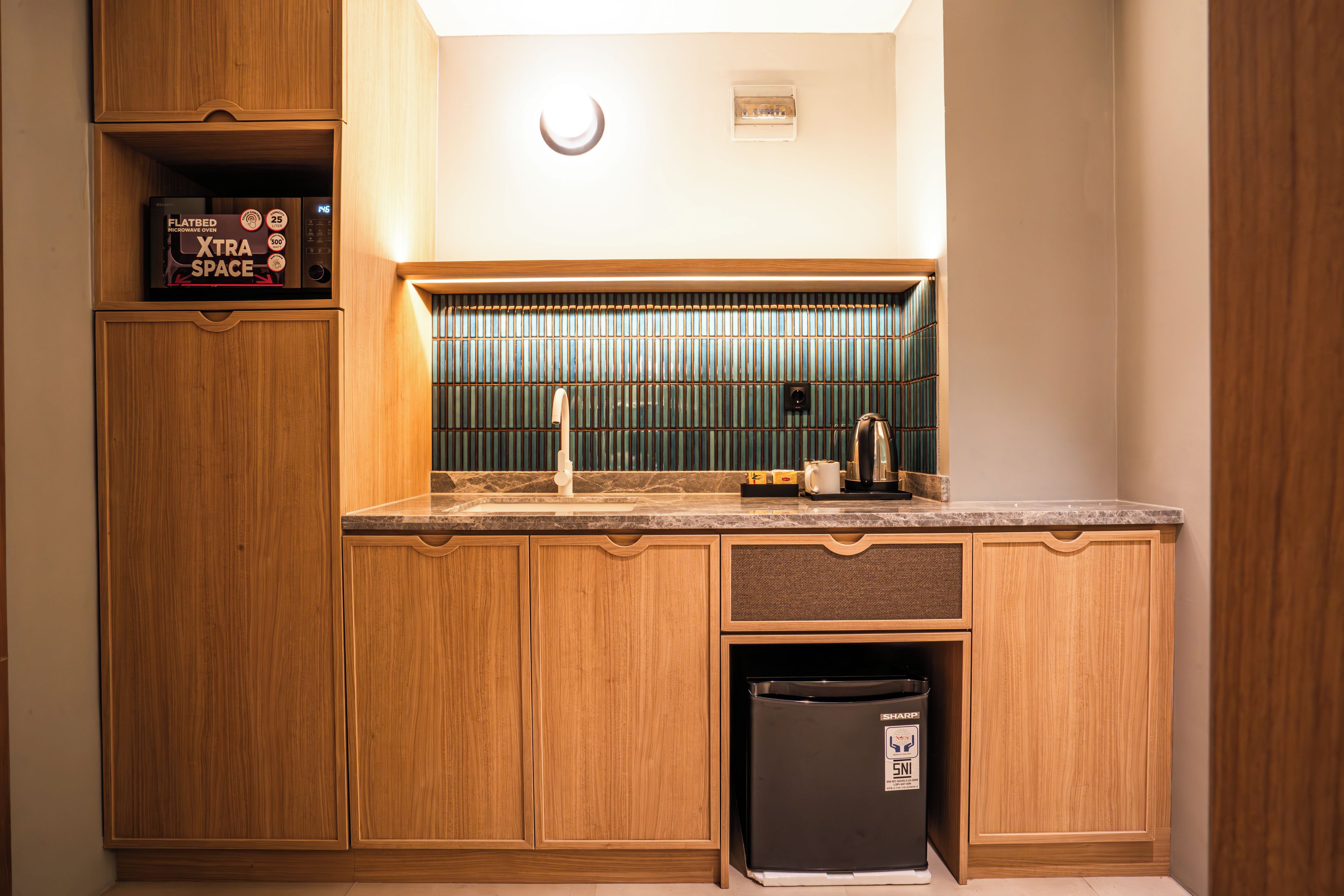 Una cocina compacta con armarios de madera, microondas y horno empotrado.