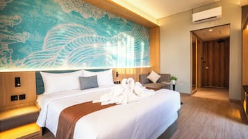 Habitación de hotel con una cama grande, un mural en la pared, una mesita de noche con una planta y una puerta que da a otra habitación.