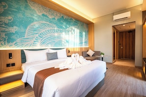 A hotel room with a large bed, a wall mural, a bedside table with a plant, and a door leading to another room.