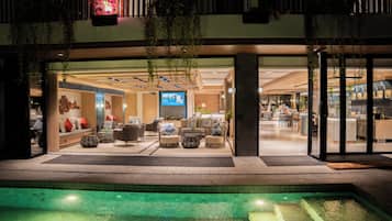 Un vestíbulo de hotel con zonas de estar, piscina y mostrador de recepción.