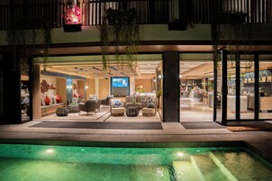 En hotellobby med sittgrupper, en pool och en receptionsdisk.