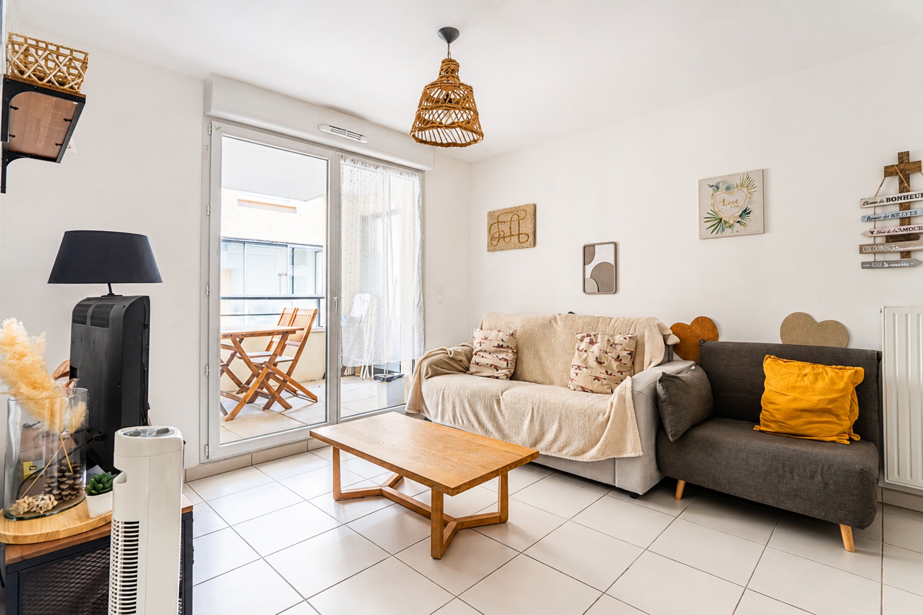 A modern living room with a sofa, a coffee table, a TV, and a balcony with a view.