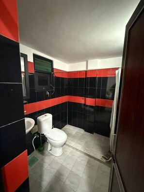Een badkamer met toilet, wastafel en spiegel.