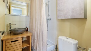 Ein Badezimmer mit einem großzügigen Waschbecken, einer Dusche und einer Toilette.