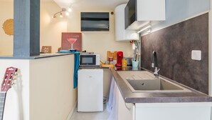 Eine kompakte Küche mit einer eingebauten Mikrowelle, einem kleinen Kühlschrank, einem Spülbecken mit modernem Wasserhahn und einer Wand-Klimaanlage.