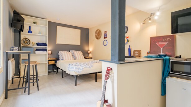 Ein gemütliches Schlafzimmer mit Bett, Nachttischen, einem Schreibtisch und einer Gitarre.