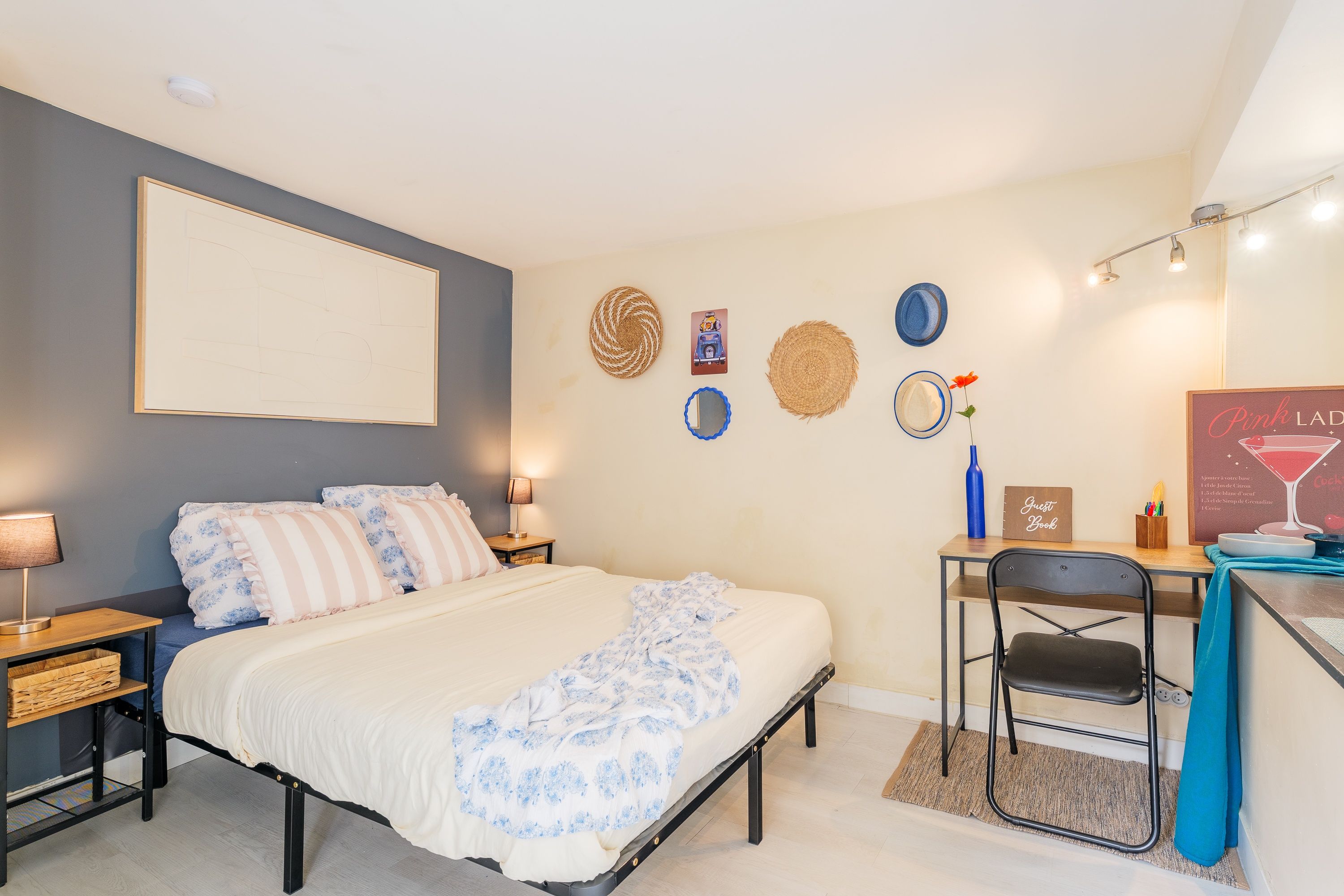 Une chambre à coucher comprenant un lit, des tables de chevet, un bureau avec une chaise, une étagère fixée au mur et une horloge murale.