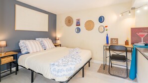 Ein Schlafzimmer mit einem Bett, Nachttischen, einem Schreibtisch mit Stuhl, einem Wandregal und einer Wanduhr.