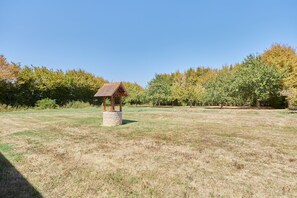 Un piccolo gazebo in legno con base in pietra in un prato erboso.