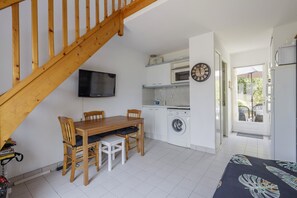 Eine kompakte Küche mit Waschmaschine, Mikrowelle und einem Fernseher an der Wand.