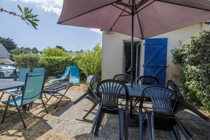 Eine Außenpatio mit Tisch und Stühlen, einem überdachten Bereich und einer blauen Tür.