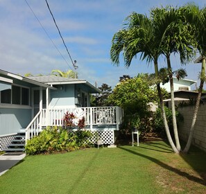 Ein Haus mit Veranda, einem kleinen Garten und einer Palme.
