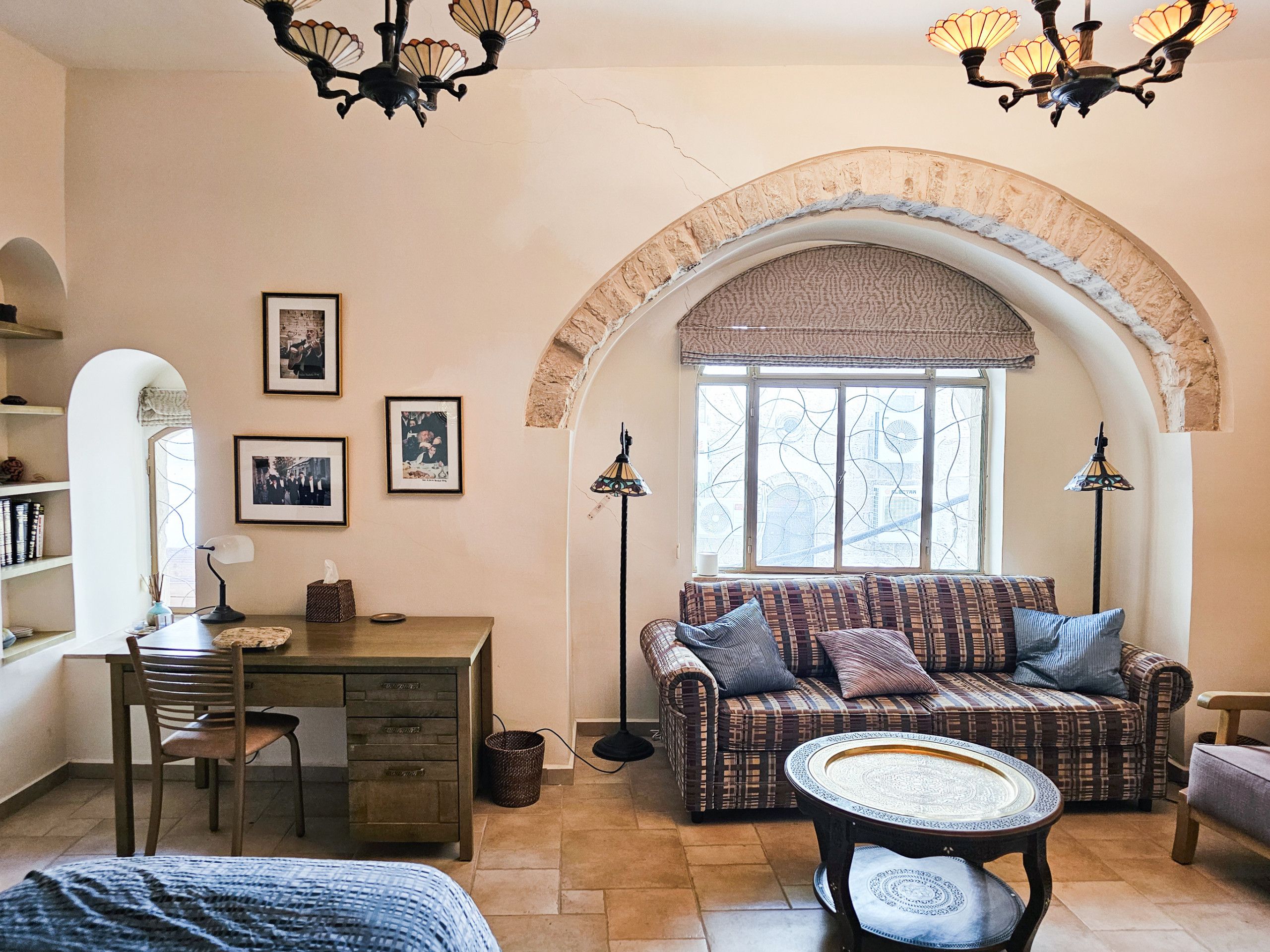 A cozy living room with a sofa, a coffee table, a desk, and a bookshelf.