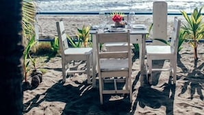 A beachside table with chairs and a table setting, overlooking the ocean. - Casita de Playa Bomalu (Las Peñitas)