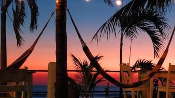 A beach setting with a hammock, chairs, and string lights.
